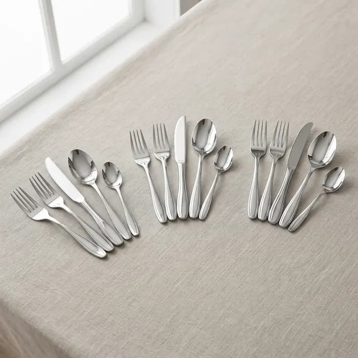 Polished stainless steel cutlery sets on a linen tablecloth